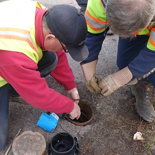 Photo of two men preforming water testing on roadway Photo of two men preforming water testing on roadway